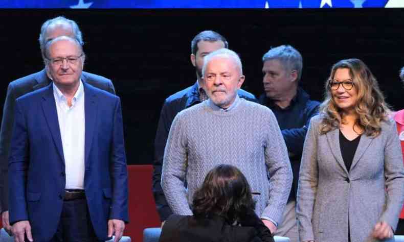 Da esquerda para a direita: Alckmin, um homem alto e calvo de terno azul, ao seu lado Lula, usando um sueter cinza, e ao lado dele a sua esponsa janja com um blazer cinza 