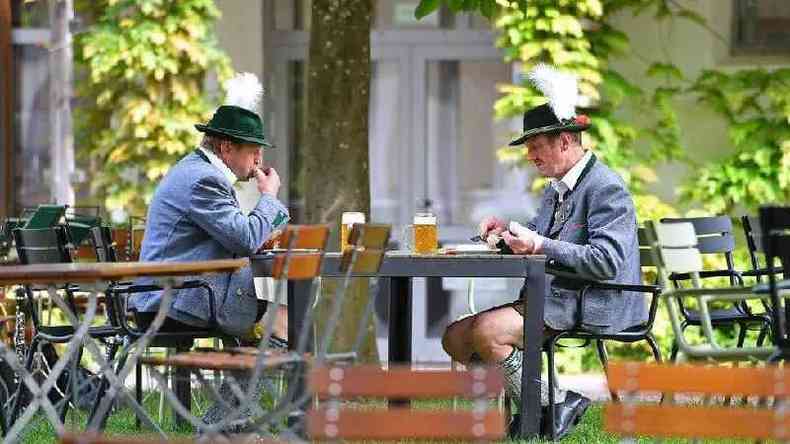 Homens com veste tpica da Baviera comendo e tomando cerveja