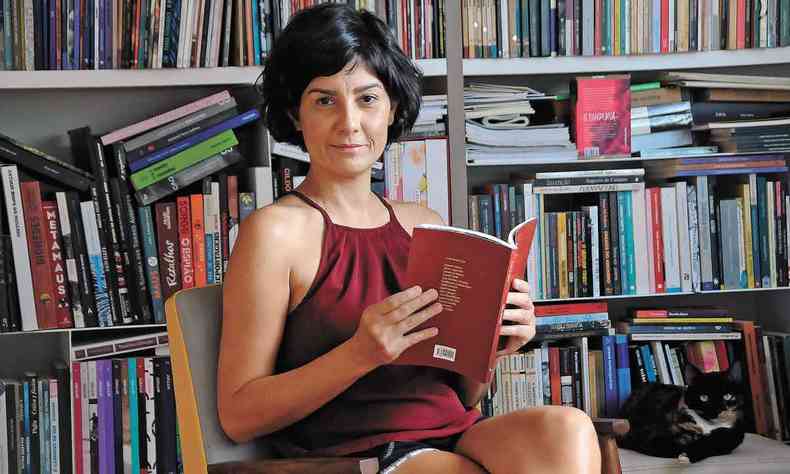 A escritora belo-horizontina Mnica de Aquino, sentada, com um livro aberto
