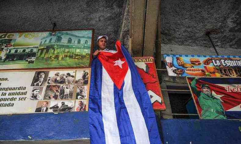 Homem coloca uma bandeira nacional cubana em seu restaurante em Havana, dois dias depois da morte do lder cubano Fidel Castro(foto: AFP / YAMIL LAGE)
