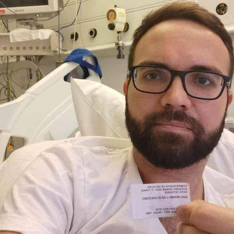 Guilherme Di Giacomo mostra comprovante de votao no hospital