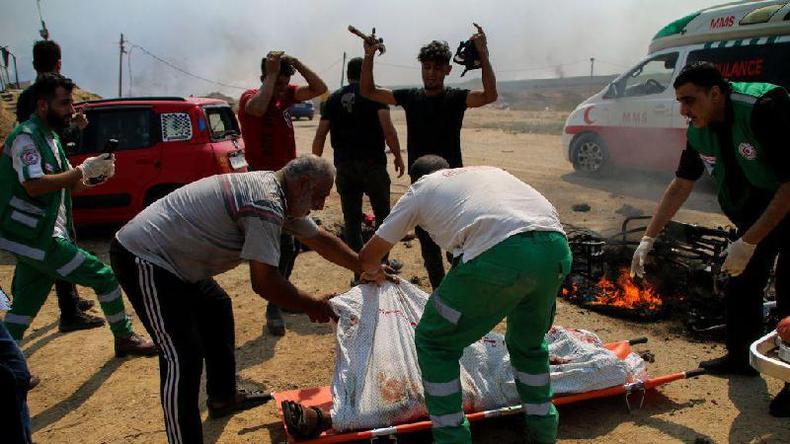Paramdicos transportam os corpos de dois jovens palestinos cuja motocicleta foi atacada perto da cerca da fronteira entre a Faixa de Gaza e Israel 