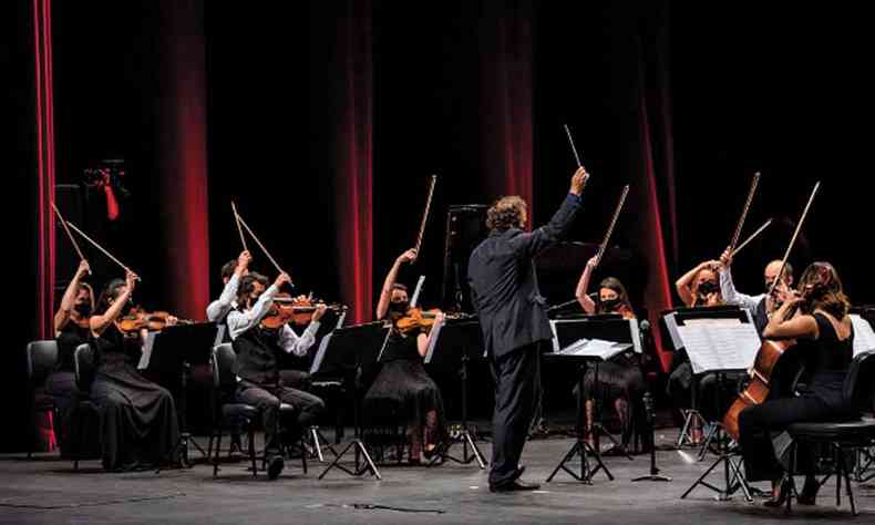 Msicos da orquestra Ouro Preto erguem seus instrumentos no palco 