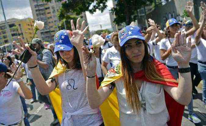 Pessoas vestem branco e levantam as mos em novo protesto contra o governo em Caracas(foto: Leo Ramirez/AFP)