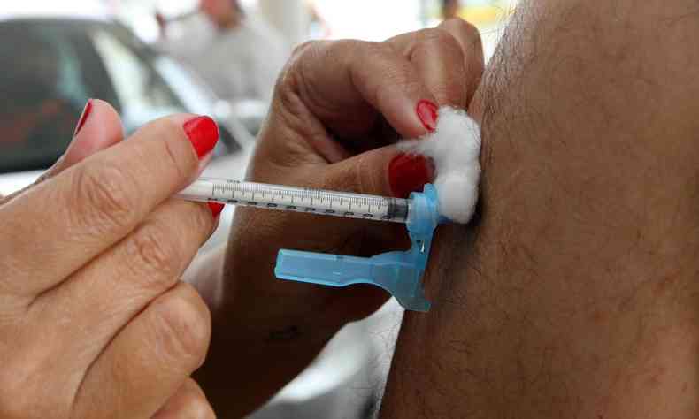 enfermeira aplica vacina com seringa contendo a vacina Pfizer