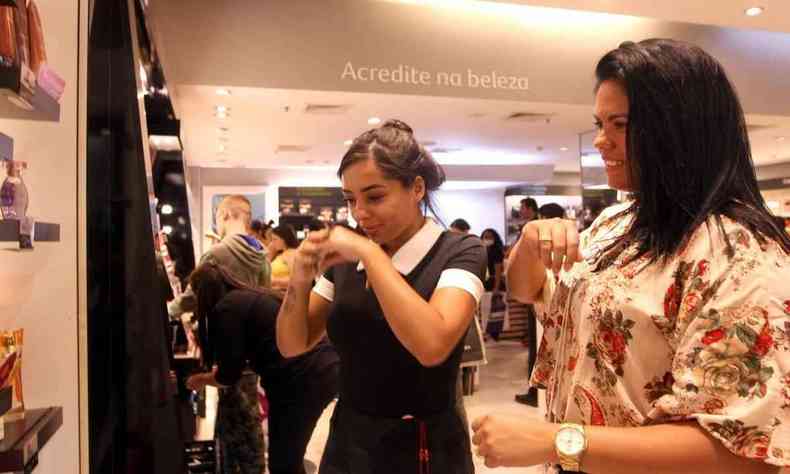 Mulheres escolhem perfume em loja de shopping