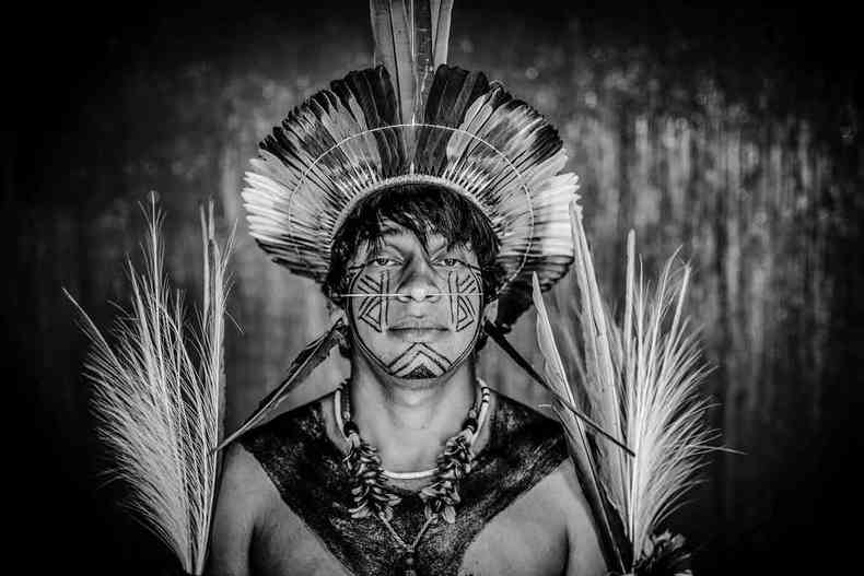 Indígena com o corpo pintado e cocar olha para a câmera, em foto de Ricardo Stuckert