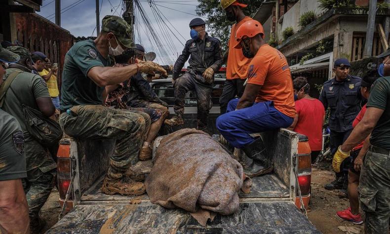 Socorristas transportam corpo de um dos mortos na tragdia das chuvas no litoral paulistano