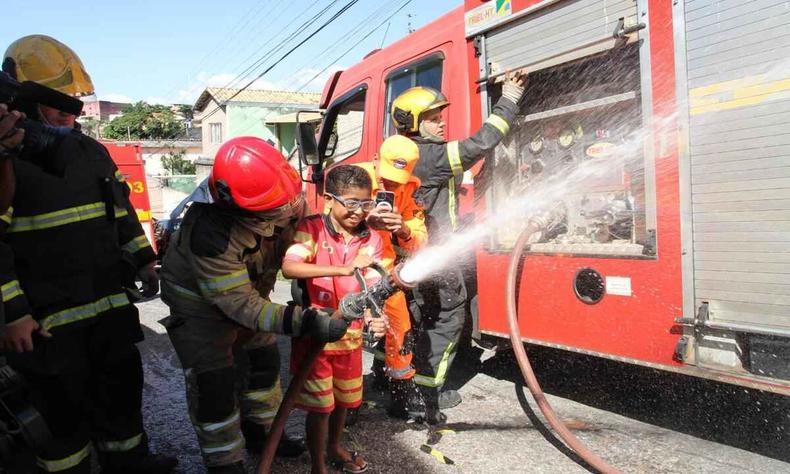 caio com a mangueira do corpo de bombeiro jorrando gua 