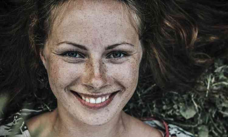 mulher com rosto cheio de sardas sorrindo
