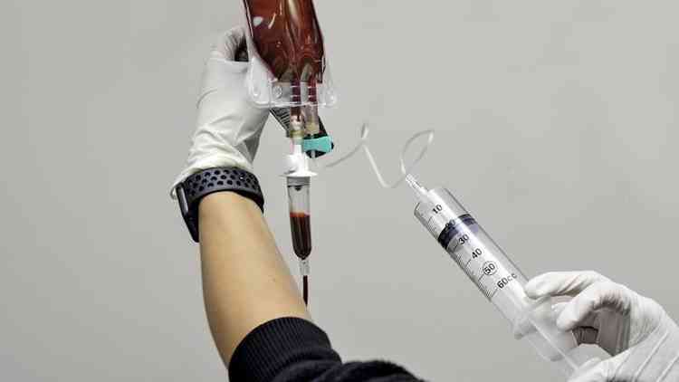 Pessoa aplicando seringa de oznio em bolsa de sangue