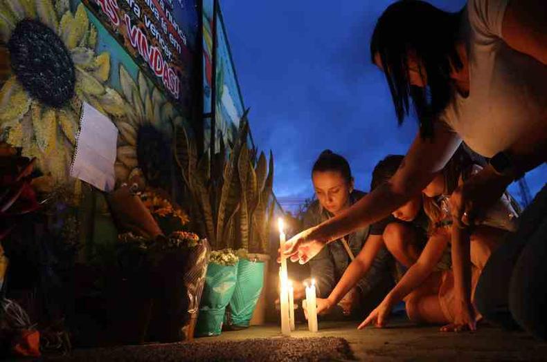 Pessoas acendendo velas em frente  creche