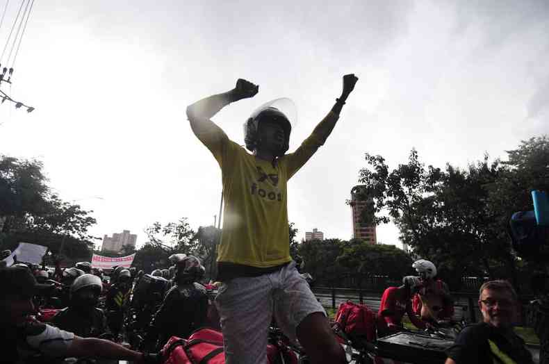 Motociclista com braos erguidos protesta junto com colegas entregadores em Belo Horizonte sob chuva