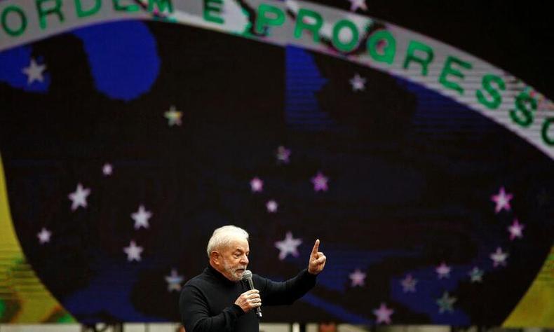 Lula fala de microfone na mo tendo ao fundo a bandeira do Brasil