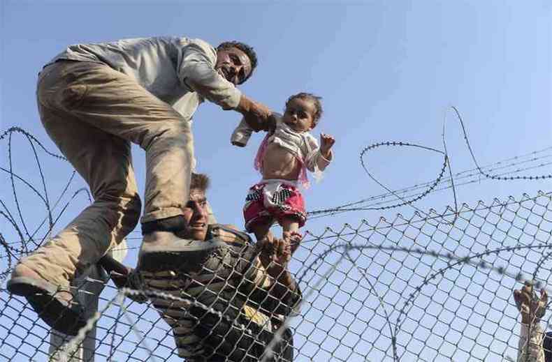 As fotos de multides de refugiados avanando entre as cercas de arame farpado da fronteira entre a Turquia e a Sria foram publicadas na capa de diversos jornais.(foto: AFP PHOTO / BULENT KILIC )