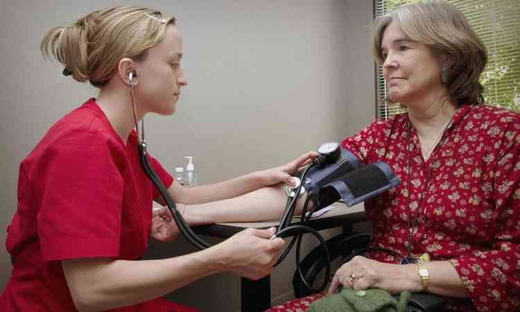 mulher idosa tendo a presso arterial medida por uma enfermeira