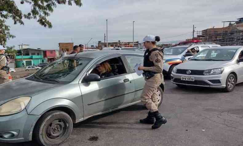 Policial militar distribuindo panfletos informativos para motorista de carro na rua