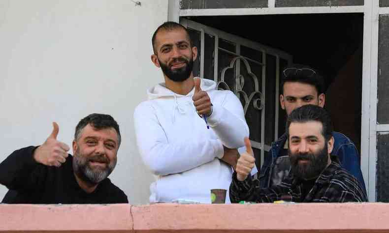 Trs atores srios da srie Pena suspensa sorriem e fazem sinal de positivo com as mos, na varanda da casa onde  gravada a produo, nos arredores de Damasco 