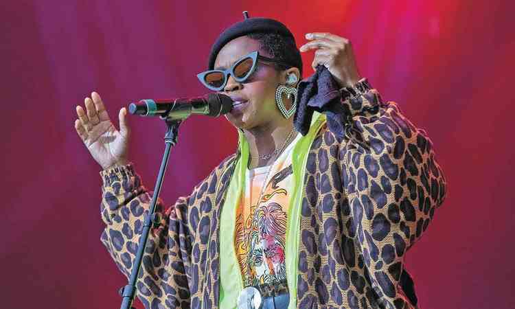 Usando casaco de oncinha, culos de gatinho e brinco gigante em forma de corao,  Lauryn Hill canta e abre os braos no palco
