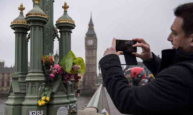 Homem fotografa homenagens s vtimas do atentado na ponte de Westminster, em Londres(foto: CHRIS J RATCLIFFE/AFP)
