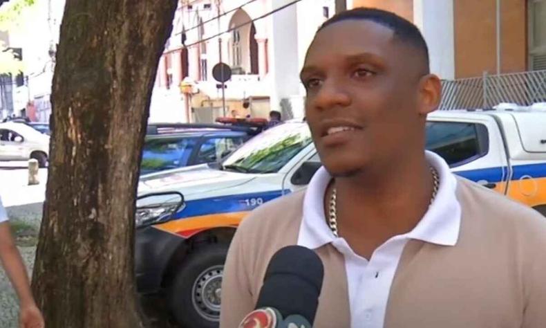 Rafael Minas de Souza, rapaz negro, em p, na rua, em Juiz de Fora, usando camisa na cor bege. 