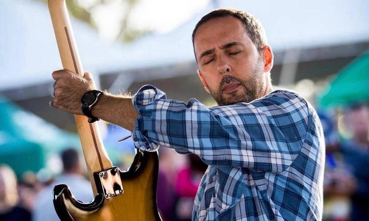 Cantor e compositor Affonsinho, de olhos fechados, posa segurando a guitarra
