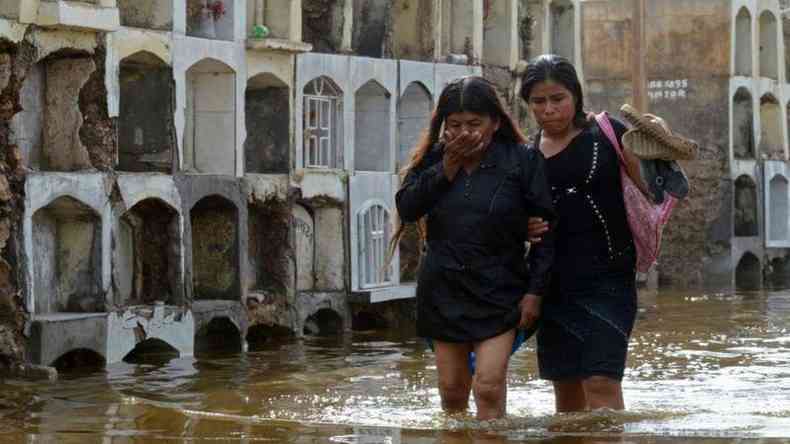Duas mulheres caminham no Peru por uma rea alagada pelas chuvas