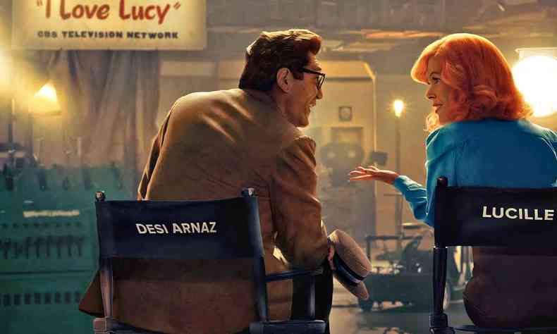 Javier Bardem e Nicole Kidman vestidos como personagens em cadeiras de diretor de cinema conversam no set de I love Lucy, no filme apresentando os ricardos 