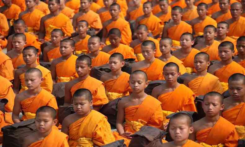 centenas de budistas, com roupa laranja e careca 