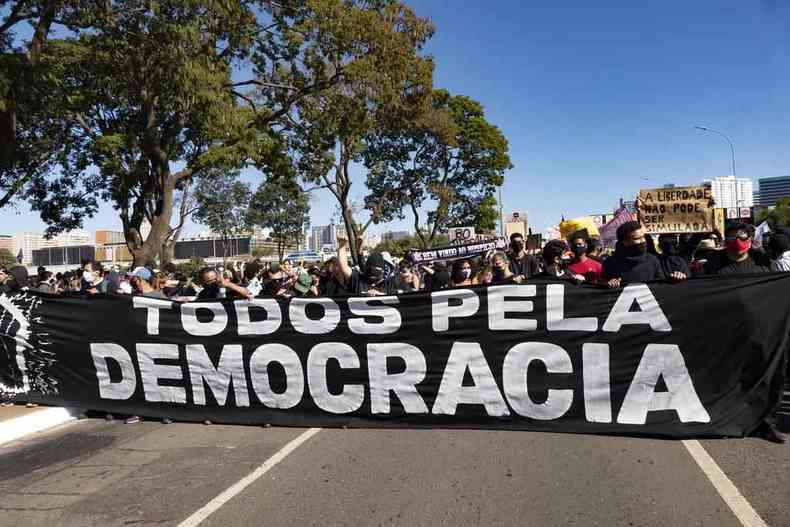 Manifestantes carregam uma faixa com a frase 'Todos pela democracia' escrita 