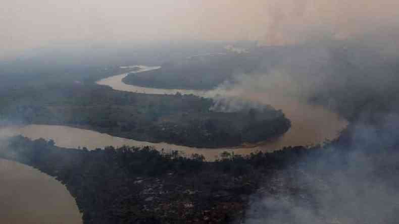 Vista area de rio no Pantanal, com florestas nas margens pegando fogo