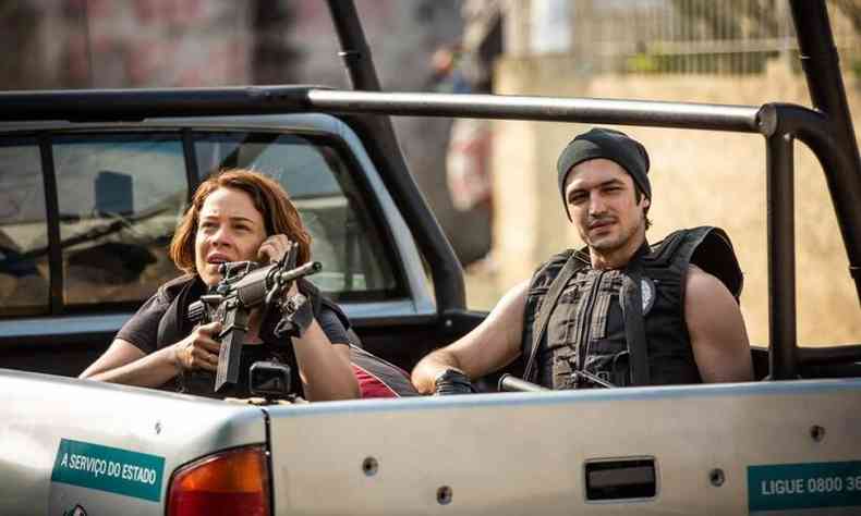 No filme Alemão 2, os atores Gabriel Leone e Leandra Leal estão vestidos de policiais e têm armas na mão na carroceria de caminhonete