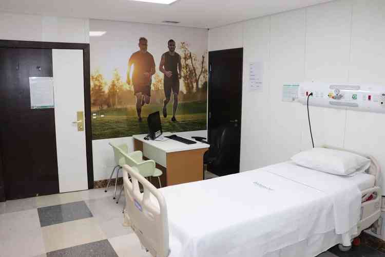 Quarto de Hospital Mater Dei com cama branca e quadro na parede