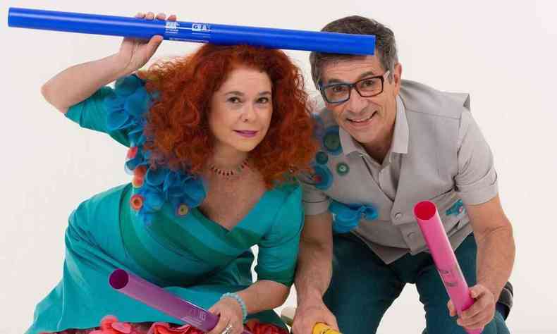 Sandra Peres, de vestido verde, e Paulo Tatit, de blusa bege, seguram brinquedos coloridos