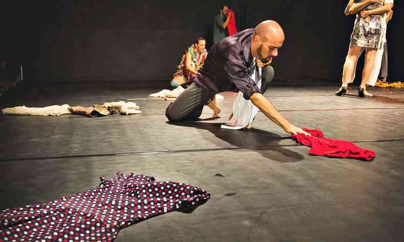 Bailarino do Grupo Primeiro Ato est no palco, ajoelhado, com as mos sobre figurino vermelho colocado no cho