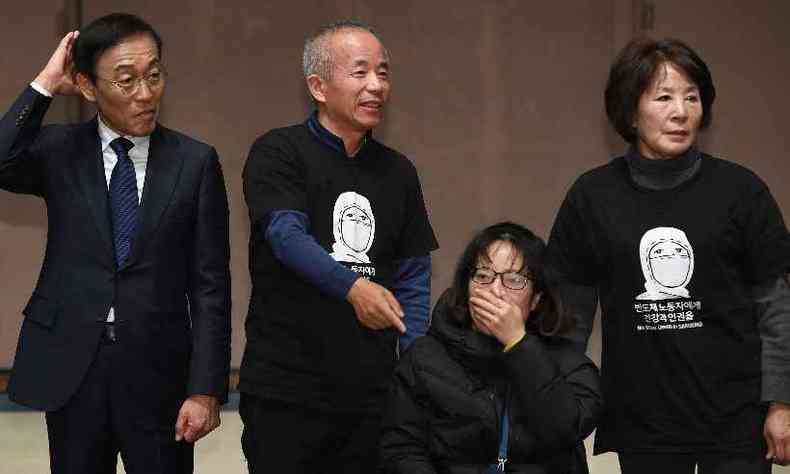 Co-presidente da Samsung Eletronics, Kim Ki-nam, posa com parentes de funcionários que tiveram doenças do trabalho nas fábricas de semicondutores e LCD(foto: Jung Yeon-je / AFP)