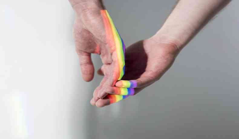 Imagem meramente ilustrativa de duas mos com tintura nas cores do arco-ris