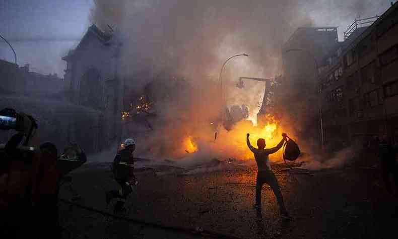 Homem comemora em frente a igreja destruda em Santiago(foto: CLAUDIO REYES / AFP )