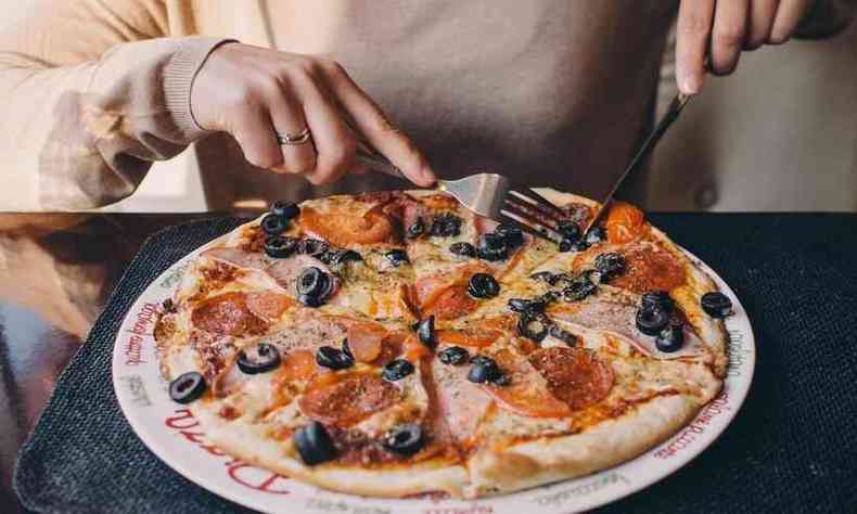 mulher comendo uma pizza grande sozinha