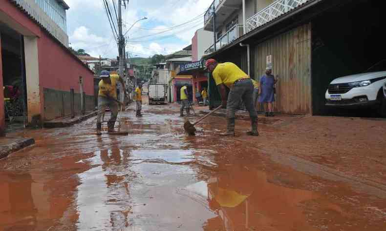 Na foto, funcionrios da prefeitura de Sabar realizam limpeza e desobstruo de rua cheia de lama da chuva