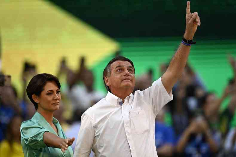 Michelle estende brao enquanto Bolsonaro aponta para o cu