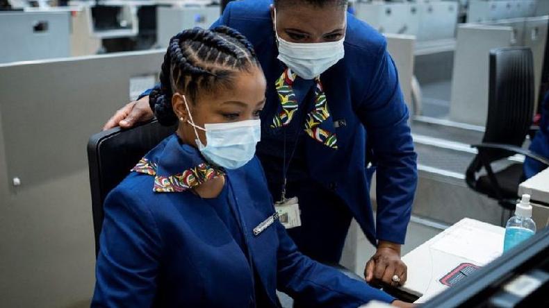 Os funcionrios da South African Airways (SAA) fazem o check-in de um passageiro (no visto) no O.R. Aeroporto Internacional de Tambo em Joanesburgo em 23 de setembro de 2021