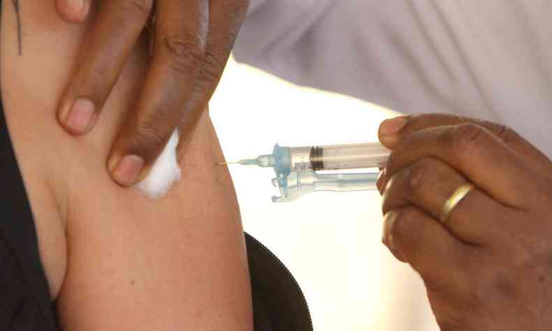 Vacina sendo aplicada no brao no posto drive-thru na UFMG