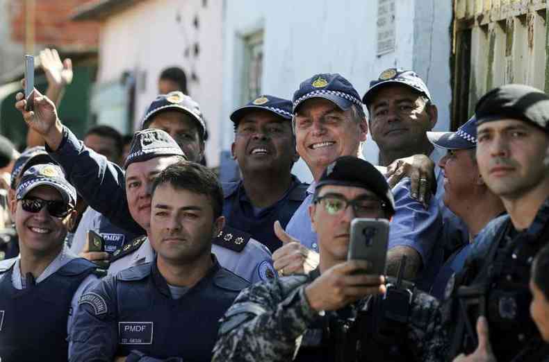Bolsonaro posa para fotos com PMs durante visita  Estrutural, em Brasilia, neste sbado(foto: Srgio Lima/AFP )