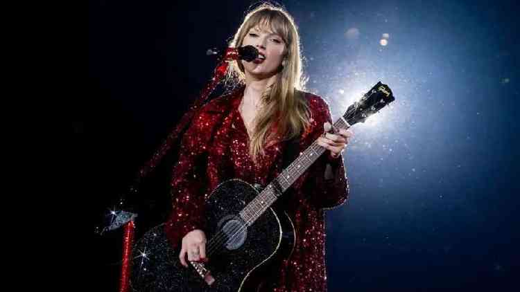 Taylor Swift cantando e tocando violão durante show