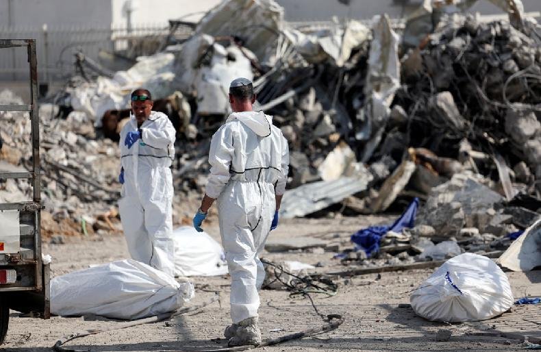 Corpos continuam a ser removidos, na cidade de Sderot, quatro dias depois dos ataques mortais feitos pelo Hamas(foto: Reuters) profissionais vestidos de branco e sacos brancos com restos mortais