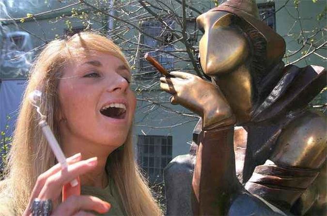 Mulher fuma em frente a uma escultura batizada 