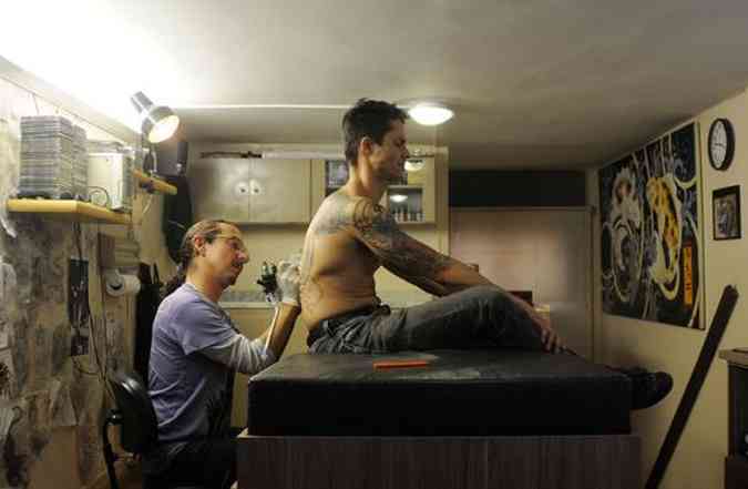 O tatuador Luck Bala tatua seu aprendiz, Simão Pedro Moreira, em seu estúdio, na Pampulha(foto: Túlio Santos/EM/D.A Press)