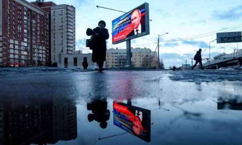 Pedestres passam por uma placa que exibe uma imagem do presidente russo Vladimir Putin e uma citao de seu recente discurso  nao: 'No tivemos outra chance a no ser agir de maneira diferente' em So Petersburgo