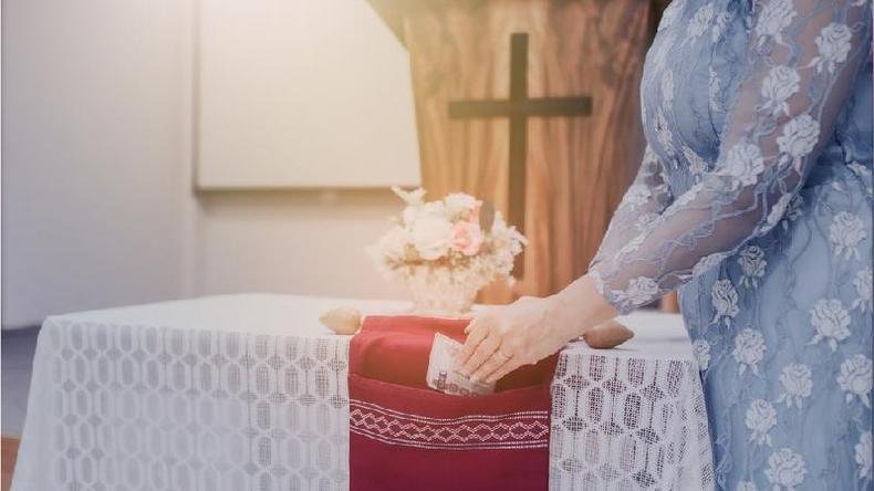 Mulher colocando doa��o em saco de oferenda da igreja